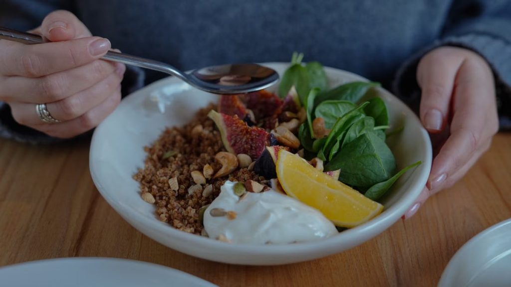 A vibrant brunch bowl with fruit, greens, and nuts for a nutritious meal.